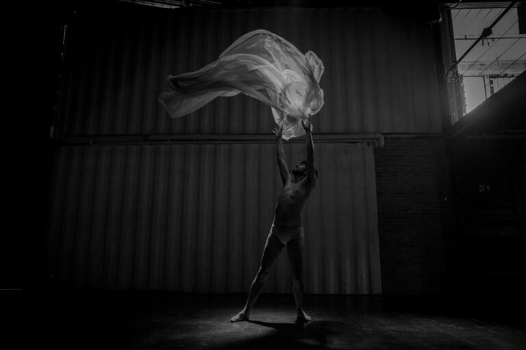 Elegant monochrome image of a dancer with flowing fabric captured in dramatic lighting.